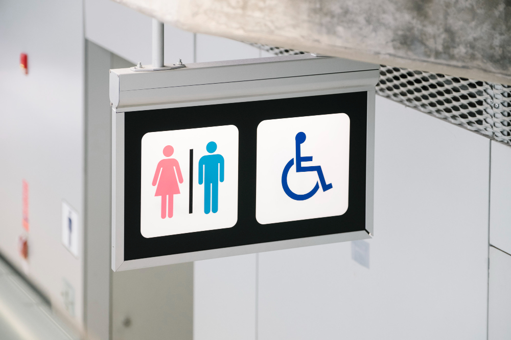 Baño accesible en centro comercial con barras de apoyo de acero inoxidable